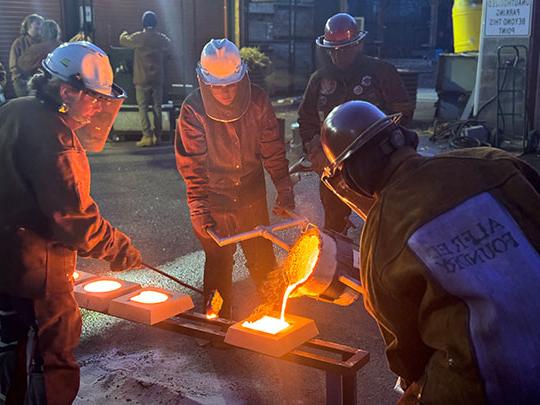 people pouring molten metal into forms